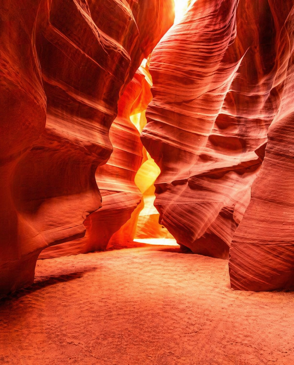 Sandstone walls of Upper Antelope Canyon glowing orange under a shaft of midday light